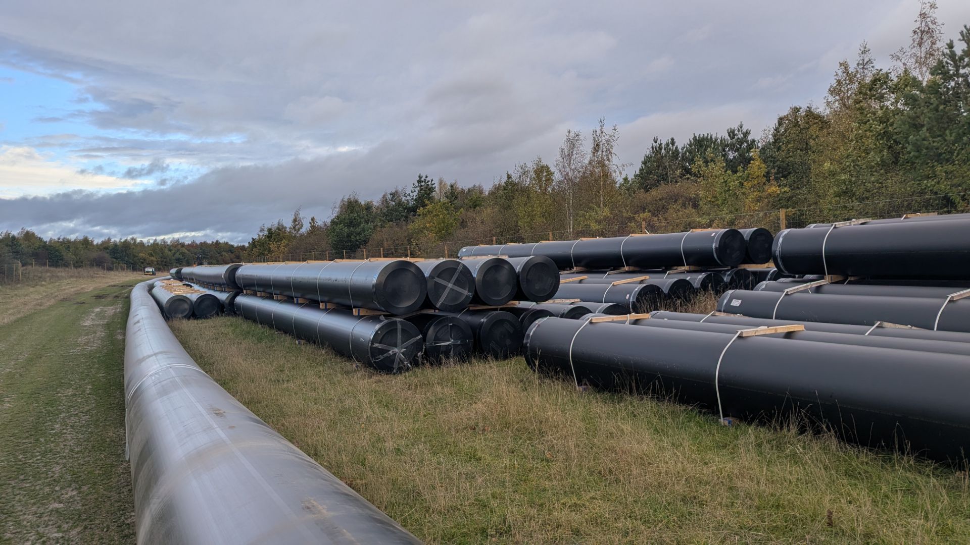 A long run of large-diameter black PE pipe strung out along the edge of a field